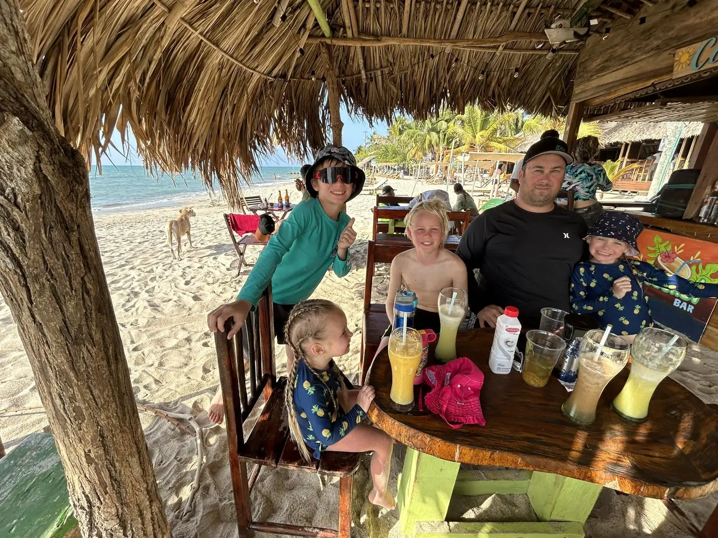 The Flip Flop Fam kids and dad at a beachside palapa in Mexico